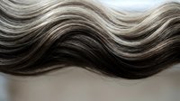Flowing wavy hair strands in natural brown and blonde highlights creating elegant texture for beauty and haircare concepts.