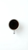 White coffee mug with black coffee viewed from above on clean white background for minimalist design projects.
