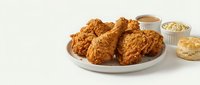 Crispy fried chicken pieces served on white plate with coleslaw, gravy, and biscuits on isolated white background for food photography and restaurant menus.