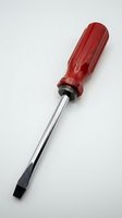Red handled flathead screwdriver with chrome steel shaft isolated on white background for tool and hardware projects.