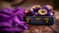 Fresh passion fruits arranged on vintage navy blue wooden box with vibrant purple fabric, dramatic lighting creates moody food photography atmosphere.
