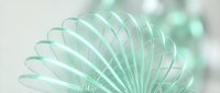 Young woman with light skin tone, wearing a mint green spring dress, holding a decorative fan against a soft blurred background for lifestyle and fashion content.
