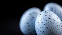 Speckled blue eggs with black dots arranged on dark background for Easter decoration and spring holiday design projects.