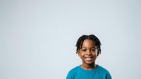Young African American boy with braided hair wearing bright turquoise t-shirt, smiling at camera against white background. Portrait suitable for educational materials, diversity campaigns, and family-oriented designs.