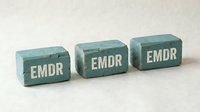 Three teal wooden blocks with white EMDR letters arranged on neutral background for therapy and mental health concept design.