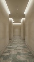 Modern minimalist corridor with recessed LED ceiling lighting and marble tile flooring in neutral beige tones for contemporary interior design projects.