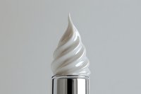 White creamy swirl on a silver metallic tube against a light gray background, evoking luxury skincare, cosmetic cream, or moisturizer product concept.