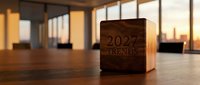 Wooden cube with 2024 trends text on modern office desk during golden hour sunset through large windows creating warm atmospheric business planning concept.