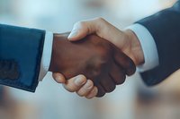 Close-up of business professionals shaking hands, symbolizing partnership, agreement, and successful negotiation in corporate environment with soft background blur.