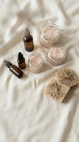 Natural spa skincare products with pink salt scrubs, essential oil bottles and handmade soaps arranged on soft linen fabric for wellness and beauty treatments.