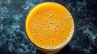 Fresh orange juice with natural foam bubbles in glass on dark textured background, top view, macro shot of citrus beverage for healthy lifestyle.
