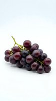 Fresh red grapes cluster with green stem isolated on white background for healthy eating and wine making concepts.