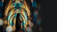 Silhouette of person standing in futuristic geometric tunnel with glowing blue and orange light patterns creating depth and perspective on dark background.