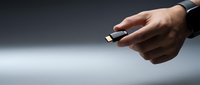 Close-up of male hand holding USB-C connector cable against neutral background for technology, connectivity, and data transfer concepts.