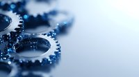 Metallic gear wheels with blue lighting effects on light background, macro shot with selective focus creating industrial technology concept for business solutions.