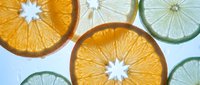 Fresh citrus slices including orange and lime rounds arranged on white background, showing vibrant pulp texture and natural fruit patterns for healthy lifestyle.