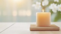 Glowing cream candle on wooden holder against soft bokeh background creates peaceful atmosphere for spa, meditation and wellness concepts.