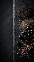Dark chocolate ingredients scattered on black slate surface with cocoa beans, nibs and powder creating artisanal confectionery composition for culinary design.