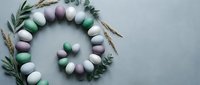 Easter egg wreath with pastel colored eggs and eucalyptus leaves on gray background. Spring holiday decoration concept for greeting cards and crafts.