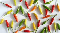 Colorful hot chili peppers scattered on white background. Fresh spicy vegetables in red, yellow, orange and green colors for cooking and seasoning recipes.