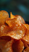 Crispy homemade potato chips with seasoning and spices in macro view. Golden-brown wavy slices with visible pepper specks on dark background. Perfect for food packaging.