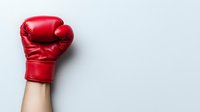 Red boxing glove raised upward against light background, symbolizing victory, strength, and determination in sports and competitive achievement.