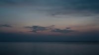 Serene twilight seascape with moody clouds and calm waters at dusk, suitable for backgrounds, travel content, and atmospheric design projects.