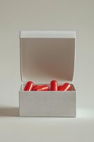 Red capsule pills in white open box against neutral background, minimalist medical and pharmaceutical concept for healthcare marketing.