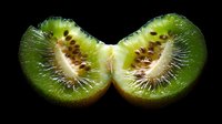Fresh juicy kiwi fruit cut in half showing detailed texture of seeds and flesh against dark background, macro food photography for healthy eating concepts.