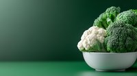 Fresh broccoli and cauliflower in white bowl on green background for healthy eating and nutrition concepts.