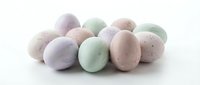Pastel colored Easter eggs in soft pink, lavender, and mint green hues scattered on white background, perfect for spring holiday decorations and celebrations.