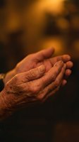 Elderly hands cupped together in warm golden light showing wrinkled skin and life experience for prayer meditation or receiving concepts.