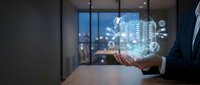 Businessman holding digital hologram of smart city with connected network icons and buildings in modern office with city skyline view at night for urban technology and innovation concepts.