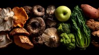 Assortment of fresh mushrooms, green apple, broccoli, bok choy, and sweet potato arranged on dark background, showcasing natural food ingredients.
