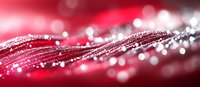Shimmering water droplets on red silky fabric create magical bokeh effect with flowing curves and sparkling light reflections in macro photography.