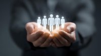 Business professional holding glowing human figures in cupped hands, representing team management, human resources, leadership, or customer relationship concept.
