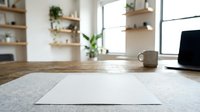 Blank white paper on wooden desk in bright modern office workspace with laptop, coffee mug, and plants for mockup and branding design projects.