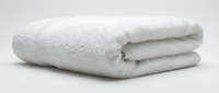 Soft white fluffy bath towel neatly folded on a light background, conveying cleanliness, comfort, and luxury for spa and hotel concepts.