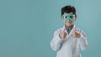 Young male scientist in white lab coat and safety goggles giving thumbs up gesture on turquoise background for educational and research concepts.