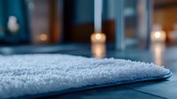 Soft white cotton towel on wooden surface with glowing candles creating cozy spa atmosphere. Wellness and relaxation concept for bathroom interior.
