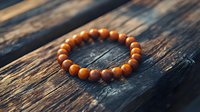 Wooden beaded bracelet on dark rustic wooden surface in warm sunlight. Natural brown prayer beads showcase minimalist spiritual jewelry design.