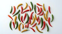 Colorful hot chili peppers scattered on white background. Fresh spicy vegetables in red, green and yellow colors isolated for culinary design projects.