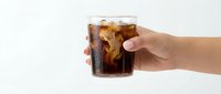 Hand holding glass of cola with ice cubes on white background, isolated beverage ready for design use on packaging, advertising, menus.