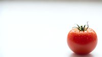 Fresh red ripe tomato with water droplets on clean white background. Healthy organic vegetable for cooking, salads and nutrition concepts.