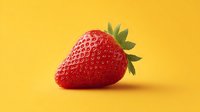 Fresh ripe strawberry with green leaves on bright yellow background. Healthy organic fruit for summer recipes, smoothies and desserts.