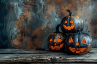 Spooky Halloween jack o'lanterns with glowing orange faces stacked on rustic wooden surface against dark moody background, perfect for seasonal holiday marketing and decoration inspiration.