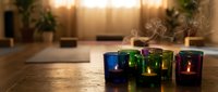 Colorful glass candle holders with burning candles create warm ambient lighting on wooden surface in cozy home interior setting for relaxation and decor.