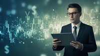 Professional businessman with glasses using tablet analyzing financial data charts and currency symbols for investment strategy and market research.