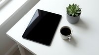 Modern workspace with tablet, coffee cup and succulent plant on white desk near window for productivity and remote work lifestyle.