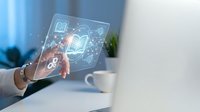 Woman holding transparent digital tablet displaying glowing education icons including books, graduation cap, and learning symbols in modern office workspace.